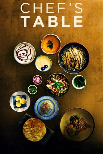 The poster features a warm, golden-brown background with an array of colorful, appetizing dishes arranged in a circular pattern. The text "CHEF'S TABLE" is prominently displayed at the top in bold, white letters. The overall mood is inviting and appetizing, suggesting a culinary-focused televisio...