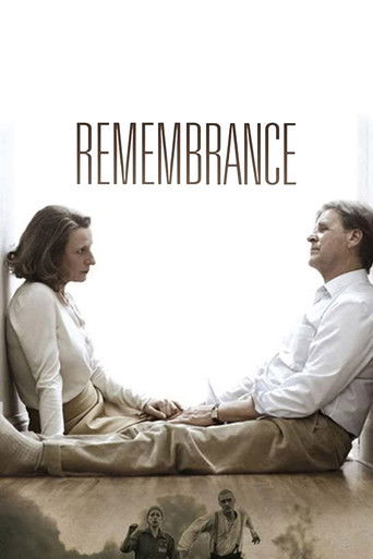 The poster features two people sitting cross-legged on a wooden floor, facing each other with a somber, reflective mood. The warm, muted tones of the image evoke a sense of quiet introspection and historical weight. The title "REMEMBRANCE" is prominently displayed at the top, reinforcing the film...