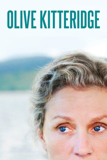 The poster features a close-up of Olive Kitteridge's expressive face with her eyes wide open, set against a serene backdrop of soft hills and water. The muted tones of her skin and hair, combined with the calm, natural colors, evoke a sense of introspection and quiet contemplation.