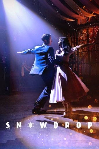 A couple dances in a dimly lit theater, illuminated by dramatic spotlights. The man wears a bright blue suit, while the woman sports a flowing red dress. The poster captures a romantic, intimate moment with soft bokeh lights in the background.