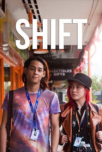 The poster features two young people walking through a vibrant, sunlit street. The man on the left wears a colorful tie-dye shirt, while the woman on the right sports a black hat and a brown jacket. Their expressions are serious yet hopeful, suggesting a journey of discovery and change. The bold ...