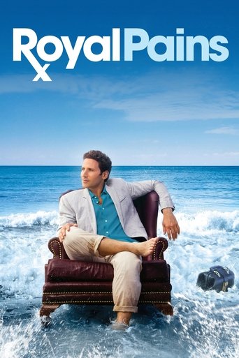The poster features a man in a white suit and blue shirt sitting on a wooden chair amidst crashing waves, evoking a sense of adventure and humor. The vibrant blue sky and ocean backdrop enhance the lively and energetic mood of the show.