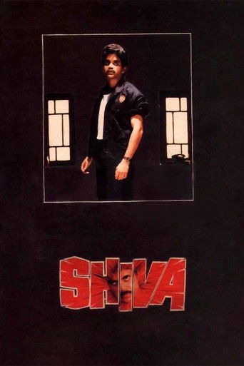 The poster features a man in a black shirt and white tie standing against a dark background, framed by two windows. Below him, the title "SHIVA" is boldly displayed in red, evoking a mysterious and dramatic mood.