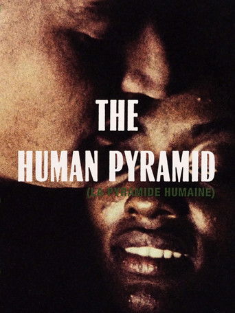 The poster features a dark, moody image of a man's face, conveying a sense of mystery and intensity. The title "THE HUMAN PYRAMID" is prominently displayed in bold, white letters against the shadowy background. The overall mood is somber and evocative, hinting at a dramatic and possibly controver...