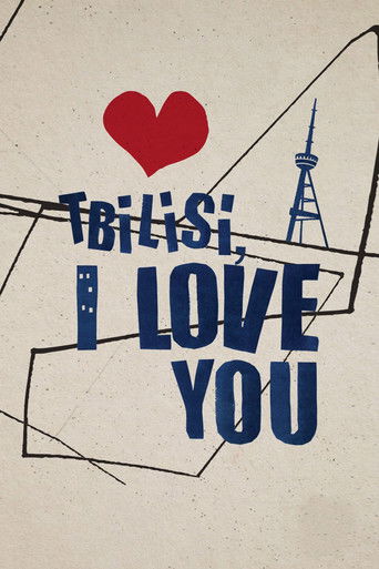 The poster features a heart-shaped red heart above the title, with a stylized tower in the background. The text is bold and blue, conveying warmth and affection. The overall design suggests a romantic and nostalgic mood, evoking the charm of Tbilisi.