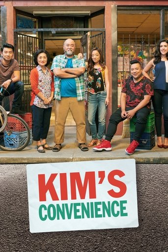 A vibrant TV show poster featuring a group of six diverse characters standing proudly in front of a storefront, with a bold "KIM'S CONVENIENCE" sign prominently displayed below. The warm, inviting colors and confident poses convey a sense of community and humor, capturing the essence of a friendl...