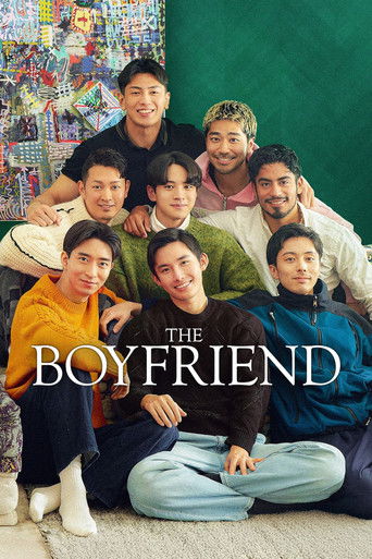 A group of young men pose together in a vibrant, colorful room with a green wall behind them. The warm lighting and cheerful expressions convey a friendly, relaxed mood. The poster features the title "THE BOYFRIEND" prominently displayed in bold, white letters across the bottom.