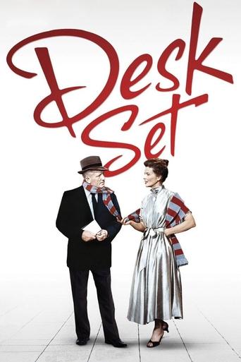 The poster features a man in a black suit and hat, and a woman in a stylish silver dress, standing against a white background. The title "Desk Set" is written in bold red letters at the top. The mood is playful and whimsical, suggesting a comedy or light-hearted narrative.