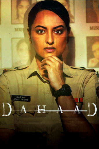 The poster features a determined woman in a police uniform against a warm, golden background. Her thoughtful expression and hand resting on her chin convey a sense of resolve and mystery. The title "Dahaad" is prominently displayed in bold, metallic lettering, suggesting a dramatic and intense na...