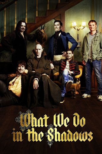 The poster features six characters in a dimly lit room with warm lighting, creating an eerie atmosphere. The characters are dressed in period clothing, suggesting a Victorian setting. The title "What We Do in the Shadows" is prominently displayed at the bottom in a gothic font.