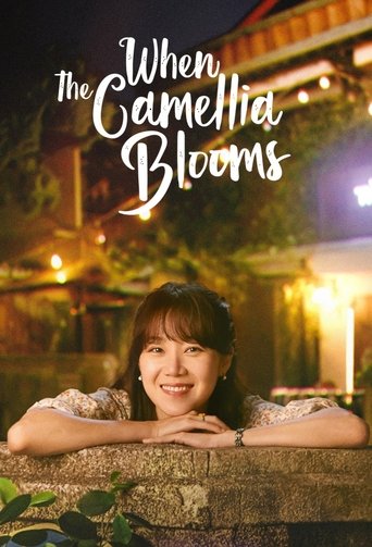 The poster features a smiling woman leaning on a stone wall at night, with warm glowing lights in the background. The title "When the Camellia Blooms" is elegantly written in white script, evoking a romantic and serene mood.