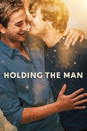 The poster features a tender moment between two men sharing an intimate kiss, with warm golden hues and sparkling particles enhancing the romantic atmosphere. The title "Holding the Man" is prominently displayed in bold white letters, emphasizing the emotional connection and love between the char...