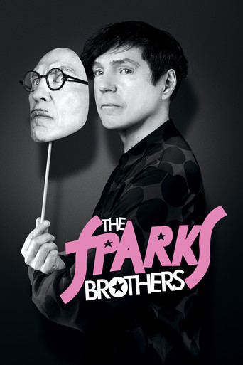 The poster features two men in a dramatic pose against a dark background. One man holds a giant, realistic-looking mask of the other, creating a surreal and intense atmosphere. The title "The Sparks Brothers" is prominently displayed in bold, pink lettering, emphasizing the film's title. The over...