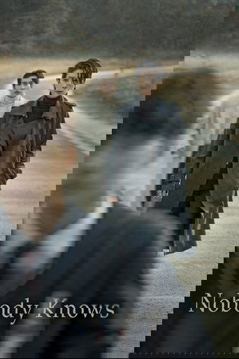 The poster features a group of three individuals walking along a deserted road, with one person in the foreground blurred. The muted earth tones and somber mood suggest a tense or mysterious atmosphere.