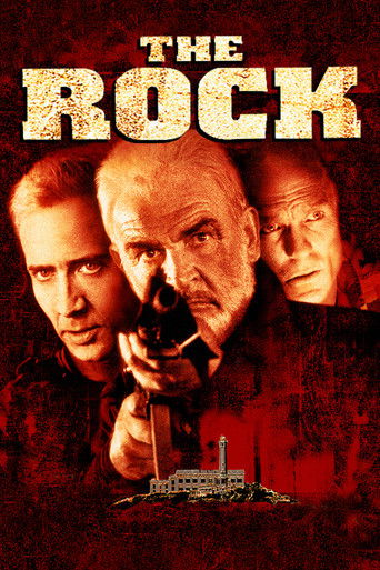 The poster features three men in a gritty, red-toned atmosphere, with one holding a gun and the others looking intense. The title "THE ROCK" is prominently displayed in bold, distressed typography.