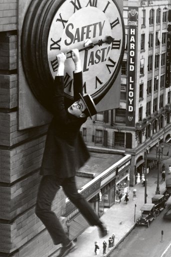 In a gritty black-and-white cityscape, a lone figure in a trench coat and boots leaps from a rooftop, clutching a giant safety clock that reads "SAFETY LAST!" The scene captures a tense, dramatic moment with a somber mood, emphasizing the urgency of the message amidst urban decay.