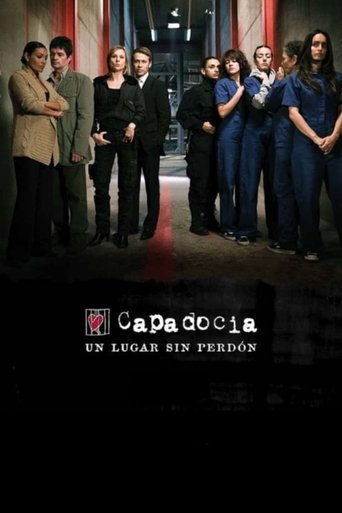 The poster features a group of six characters standing in a dimly lit room, exuding mystery and intrigue. The muted tones of the image, with dark clothing and shadowy figures, create a suspenseful atmosphere. The title "Capadocia" is prominently displayed at the bottom, hinting at the show's dark...