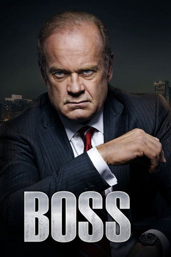 The poster features a stern, balding man in a sharp suit adjusting his watch, exuding authority and confidence. The dark background contrasts with the bright white text of the word "BOSS," creating a dramatic and intense atmosphere.