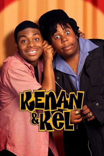 The poster features two young men with expressive faces, one in a pink shirt and the other in a dark jacket, both smiling warmly. The title "KENAN & KEL" is prominently displayed in bold, yellow letters with a black outline. The warm orange background adds a cozy, inviting atmosphere to the image.