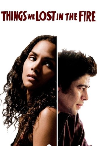 The poster features a split image of two characters, one woman with curly hair and a man with dark hair, both looking upward with intense expressions. The title "Things We Lost in the Fire" is prominently displayed at the top in bold red letters. The overall mood is dramatic and mysterious, sugge...