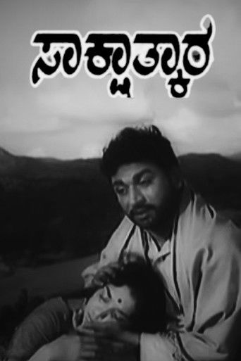 The poster features a somber black-and-white image of a man holding a woman, evoking a sense of grief and sorrow. The title "Sakshathkara" is prominently displayed in Bengali script at the top, suggesting a poignant narrative. The muted tones and the man's contemplative expression convey a deep e...