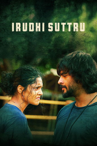 The poster features a man and woman in a lush green forest, their expressions conveying deep emotion and connection. The warm, earthy tones of the background suggest a natural, serene setting, while the title "Irudhi Suttru" hints at a story of deep emotional journey.