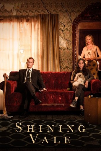 The poster features a man in a sharp suit reclining on a plush red sofa, while a woman sits beside him. In the background, a woman stands near a doorway, and a man in a suit sits on a chair. The warm lighting and rich red tones evoke a cozy yet mysterious atmosphere, hinting at the show's superna...