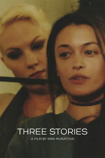 The poster features two women with intense, dramatic expressions against a muted, warm-toned background. The blonde woman on the left is partially obscured, while the brunette woman in the foreground dominates the frame with a serious gaze. The text "THREE STORIES" and "A FILM BY KIRA MURATOVA" i...
