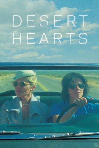 The poster features two women in a convertible car, one wearing a white hat and sunglasses, the other in a blue shirt and sunglasses. The desert landscape with a clear blue sky and white clouds provides a serene backdrop. The title "DESERT HEARTS" is prominently displayed in large white letters a...