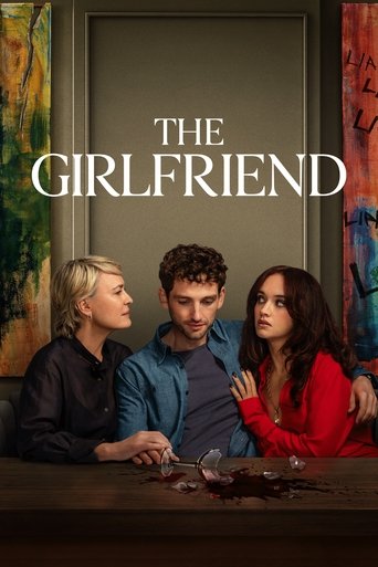 The poster features three characters seated at a table, with warm lighting and rich colors. The mood is intimate yet slightly tense, suggesting a dramatic relationship between the central figures. The title "The Girlfriend" is prominently displayed, hinting at a romantic or dramatic storyline.