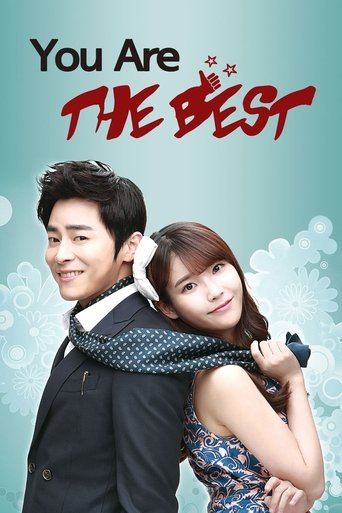 The poster features a romantic couple embracing against a soft teal background with subtle snowflakes. The man in a dark suit and the woman in a blue dress exude warmth and charm. Bold red text announces "You're the Best," evoking a playful and affectionate tone.