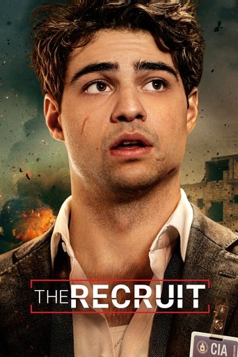 The poster features a young man with a concerned expression, his eyes wide and mouth slightly open. He wears a dark jacket over a light shirt, with a name tag reading "THE RECRUIT" prominently displayed. The background suggests a dramatic, possibly war-torn setting with fiery explosions and smoky...