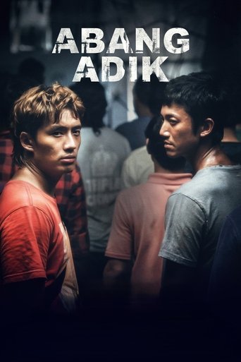 The poster features a group of young men in dimly lit, gritty settings, with warm orange and red tones creating an intense, gritty atmosphere. The title "ABANG ADIK" is prominently displayed in bold, white letters, emphasizing the film's theme of friendship and camaraderie among street children.