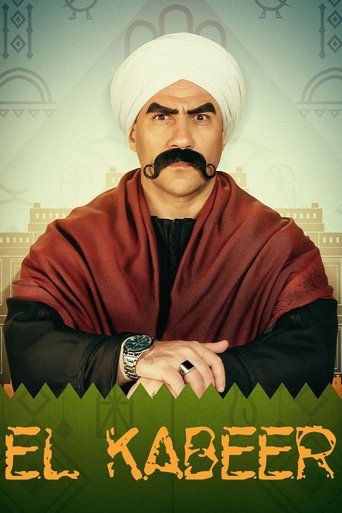The poster features a man with a mustache and white turban, wearing a red shawl over black clothing. The background shows a traditional building with green accents. The title "EL KABEEER" is prominently displayed in bold letters at the bottom. The overall mood is serious and culturally rich.