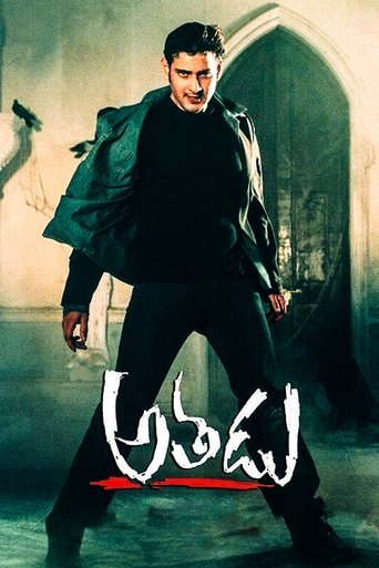 The poster features a muscular man in a dark outfit, exuding strength and intensity. The background is dimly lit with a mysterious, gothic atmosphere, enhancing the film's suspenseful tone. The title "Athadu" is prominently displayed in bold, stylized lettering, suggesting a thrilling and action-...