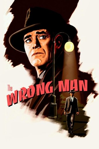 The poster features a stern, weathered man in a black hat and coat, with a mysterious figure in a suit standing in the shadows. The title "The Wrong Man" is prominently displayed in bold red letters. The overall mood is dark and suspenseful, with muted tones and dramatic lighting that evoke a sen...