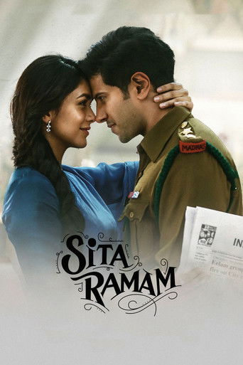 The poster features a tender moment between a woman in a blue outfit and a man in a military uniform, with their foreheads touching. The warm tones of their clothing and the soft lighting evoke a romantic and nostalgic mood. The title "Sita Ramam" is elegantly displayed in the foreground, hinting...