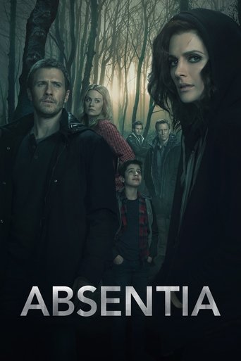 The poster depicts a group of people standing in a dark, misty forest, evoking a sense of mystery and unease. The muted colors and shadowy figures create an atmospheric mood, suggesting themes of isolation and supernatural intrigue.