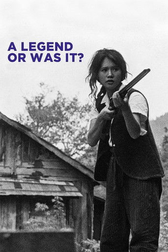 The poster features a hauntingly realistic black-and-white image of a woman with long hair, holding a shotgun over a rustic wooden structure. The stark monochrome palette and somber mood evoke a sense of mystery and danger. The text "A LEGEND OR WAS IT?" adds an intriguing twist to the scene.