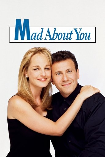 The poster features a smiling couple in a black outfit against a plain white background. The title "Mad About You" is prominently displayed in blue and white text. The mood is light-hearted and romantic, capturing the essence of the show's comedy and romance.