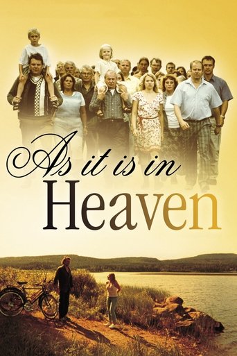 The poster features a group of people standing on a grassy hill overlooking a serene lake, with a bicycle in the foreground. The warm golden hues of the sunset evoke a sense of peace and nostalgia, while the title "As It Is in Heaven" suggests a timeless, unchanging reality.