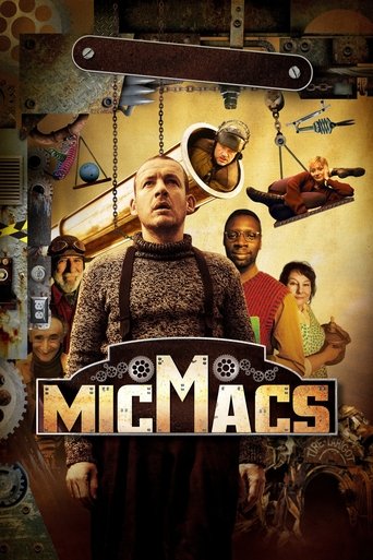 The poster features a central figure in a dark, textured outfit with a prominent "MICMACS" title. Surrounding him are six diverse characters, each holding tools or objects, suggesting a work environment. The warm, earthy tones and rustic background evoke a gritty, adventurous atmosphere.