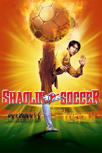 A man in a yellow shirt and blue jeans stands on a soccer field, holding a soccer ball aloft with one hand while the other is raised in a gesture of surrender. The background features a fiery orange sky with a soccer team in black uniforms in the distance. The title "Shaolin Soccer" is prominentl...