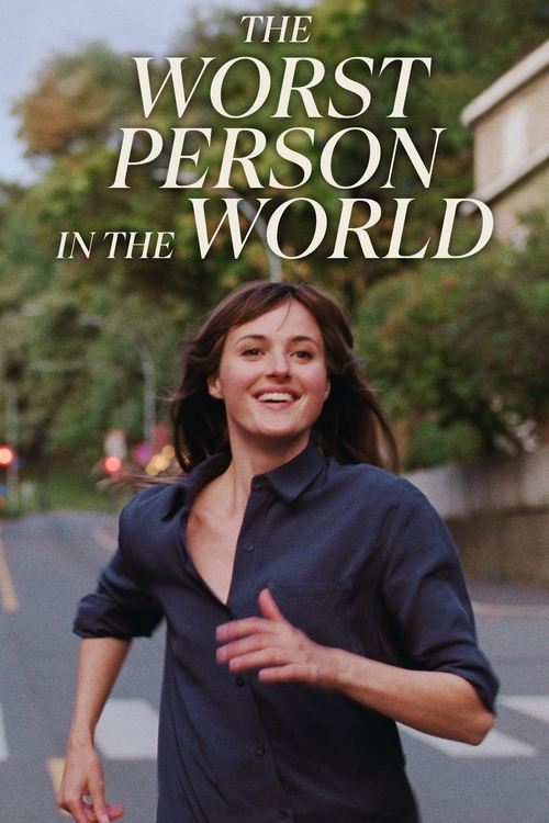 The poster features a confident woman in a dark blue shirt, exuding energy and humor. The title "The Worst Person in the World" is prominently displayed in bold, white letters against a blurred suburban background. The overall mood is lighthearted and engaging, suggesting a comedic or entertainin...