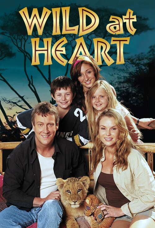 The poster features a lively family of five—adults and children—posing together in a rustic outdoor setting. The warm, golden-yellow title "Wild at Heart" dominates the top, evoking a sense of adventure and heart. The background shows a serene forest scene with a lion cub nestled between the adul...