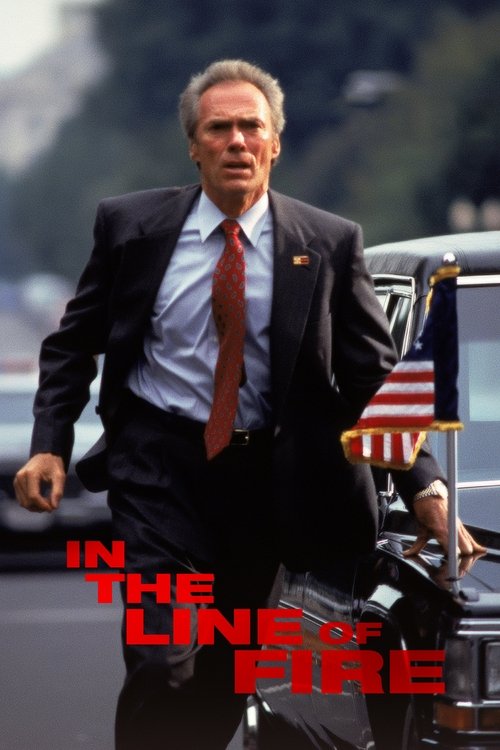 The poster features a determined man in a dark suit and red tie, walking briskly with a suitcase. The American flag is visible in the background, suggesting a patriotic theme. The title "In the Line of Fire" is prominently displayed in bold red letters, conveying urgency and danger. The overall m...