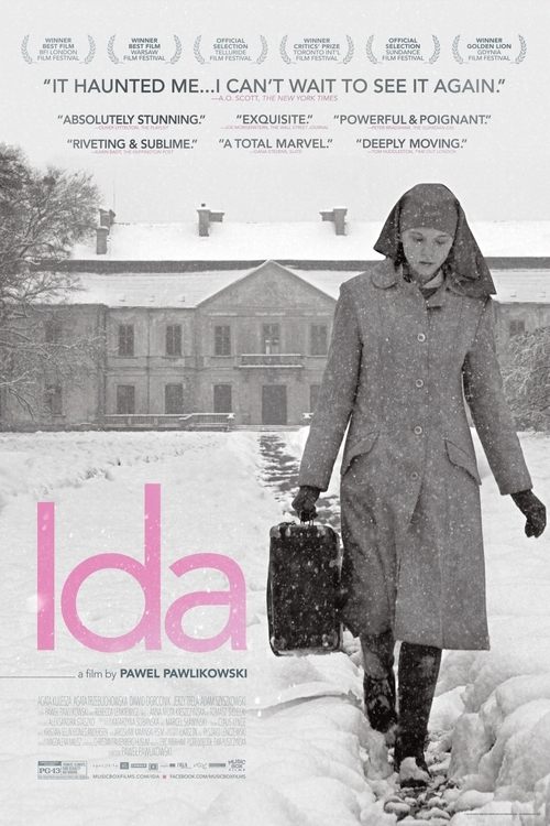 A lone woman in a trench coat walks through snow-covered streets, carrying a suitcase. The poster features a muted, desaturated color palette with stark white text and a large pink "Ida" logo. The mood is somber and reflective, suggesting themes of migration and hardship.
