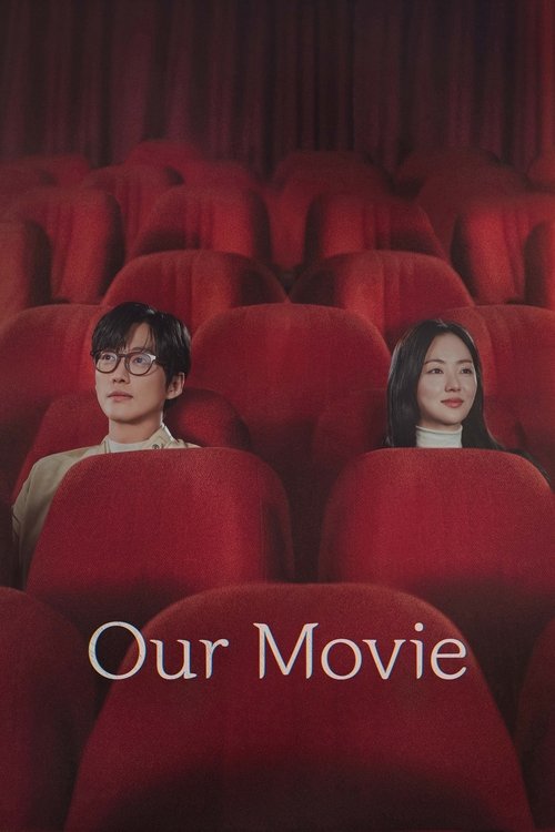 In a dimly lit theater, two people sit in red seats, watching a film. The warm red tones and soft lighting create an intimate, cinematic mood.