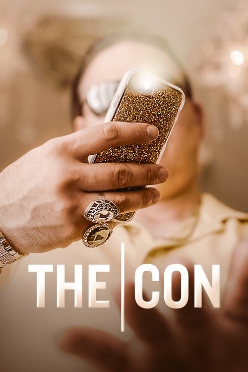 A hand holding a smartphone with a glittery screen dominates the frame, casting a warm glow against a blurred background. The scene exudes mystery and intrigue, with the title "THE CON" prominently displayed in bold, white letters. The soft lighting and muted tones create an atmospheric, suspense...