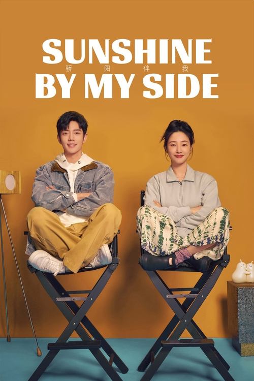The poster features two individuals seated on folding chairs against a warm, mustard-yellow background. The man on the left wears a gray sweater and tan pants, while the woman on the right dons a light-colored blouse and patterned skirt. Their expressions are relaxed and friendly, suggesting a ca...